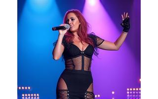 Pop star on stage with dazzling concert lights.